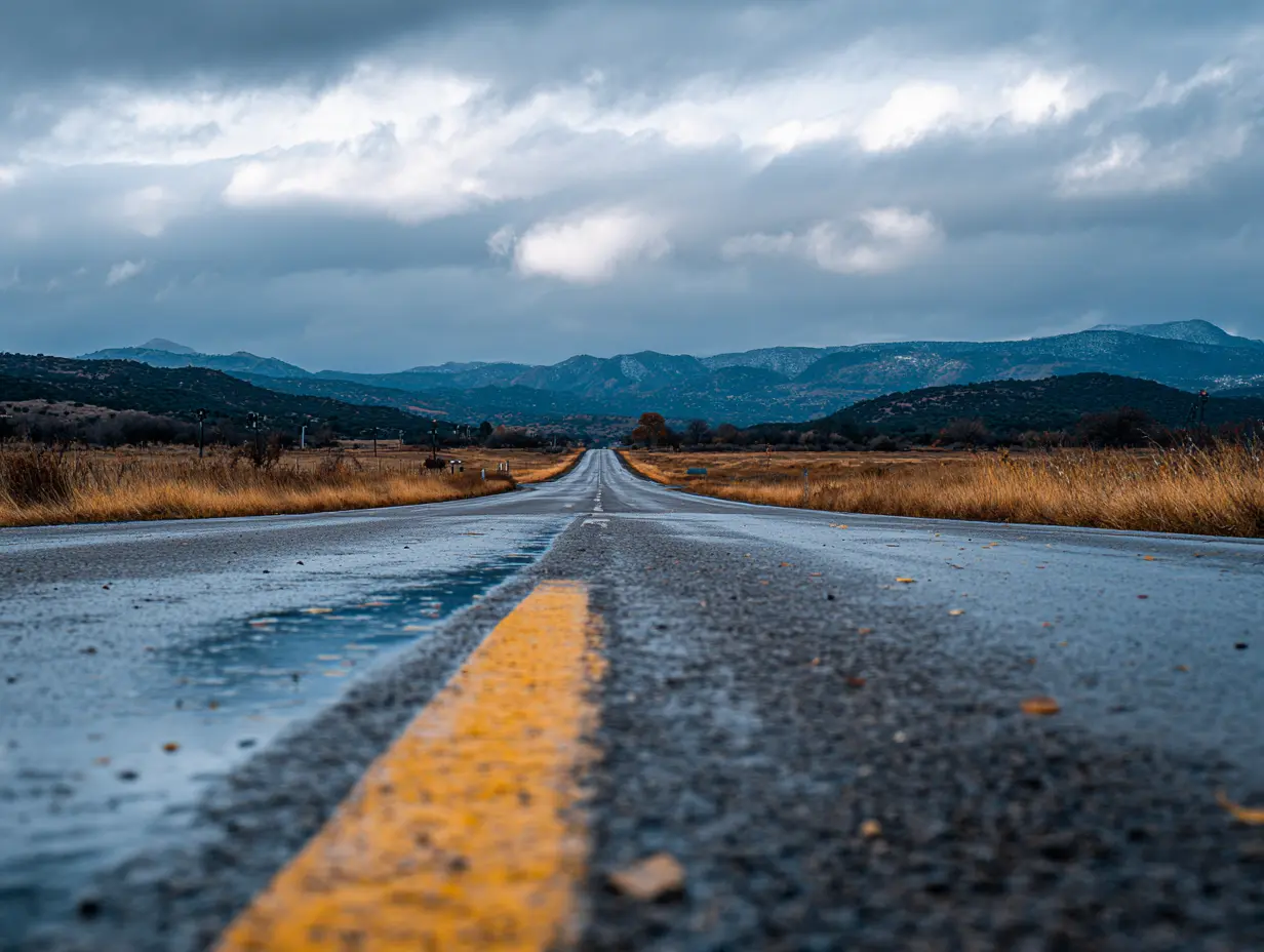 Rainy road with a vast view of mountains, and clouds.